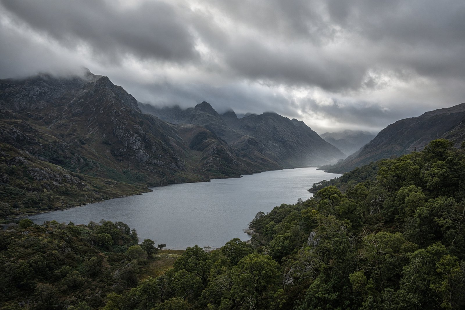 Dark slate peaks above a long glacial lake and oak woods